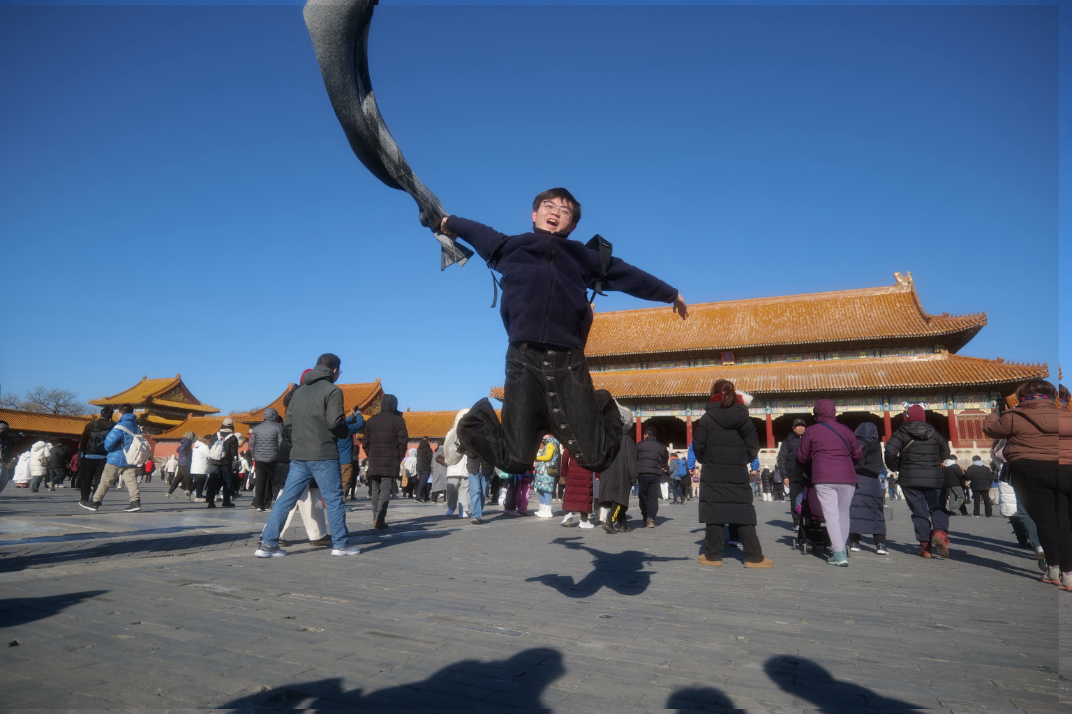 郑越在蓝天下跃起,身后是金色屋顶的建筑与人群